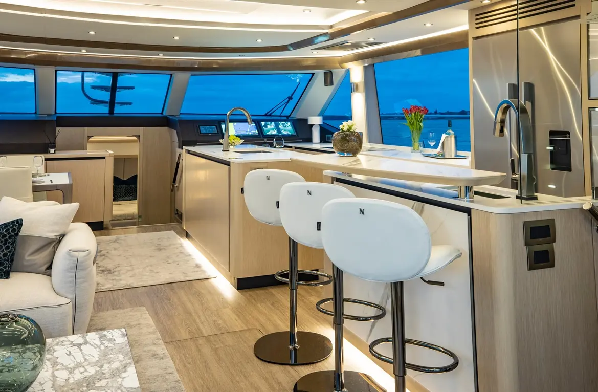 Stylish yacht interior featuring a modern kitchen with bar stools, large windows, and a warm, inviting atmosphere.